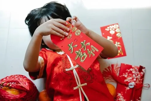 Dziecko otwiera czerwoną kopertę ozdobą