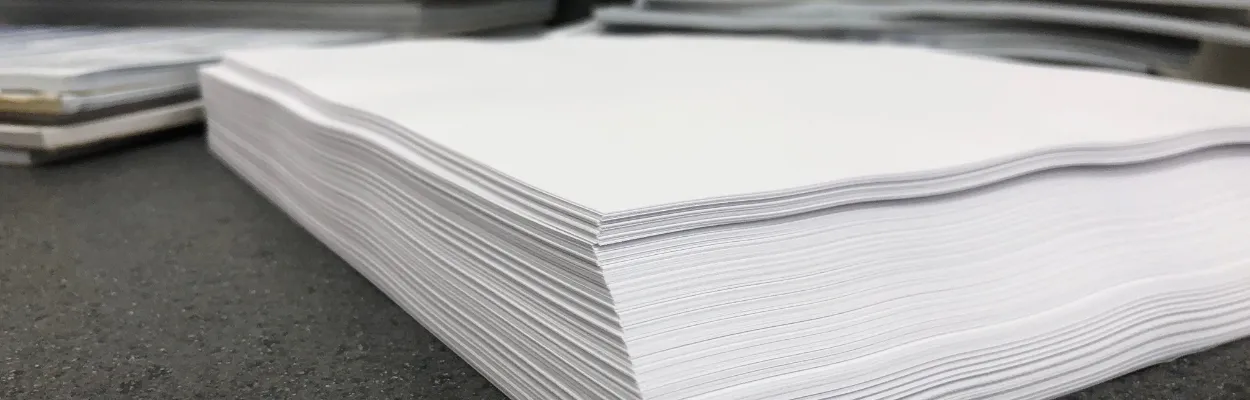 Ryza papieru leżąca na biurku wśród dokumentów