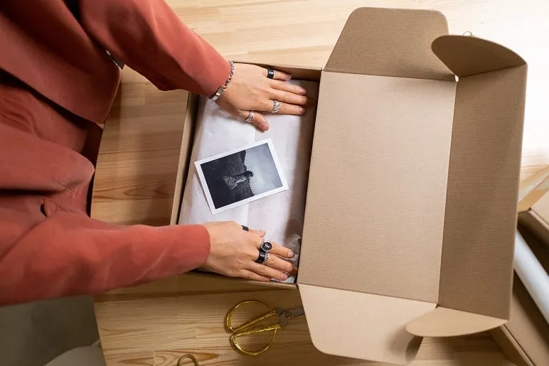 Osoba pakuje odzież do pudełka e-commerce