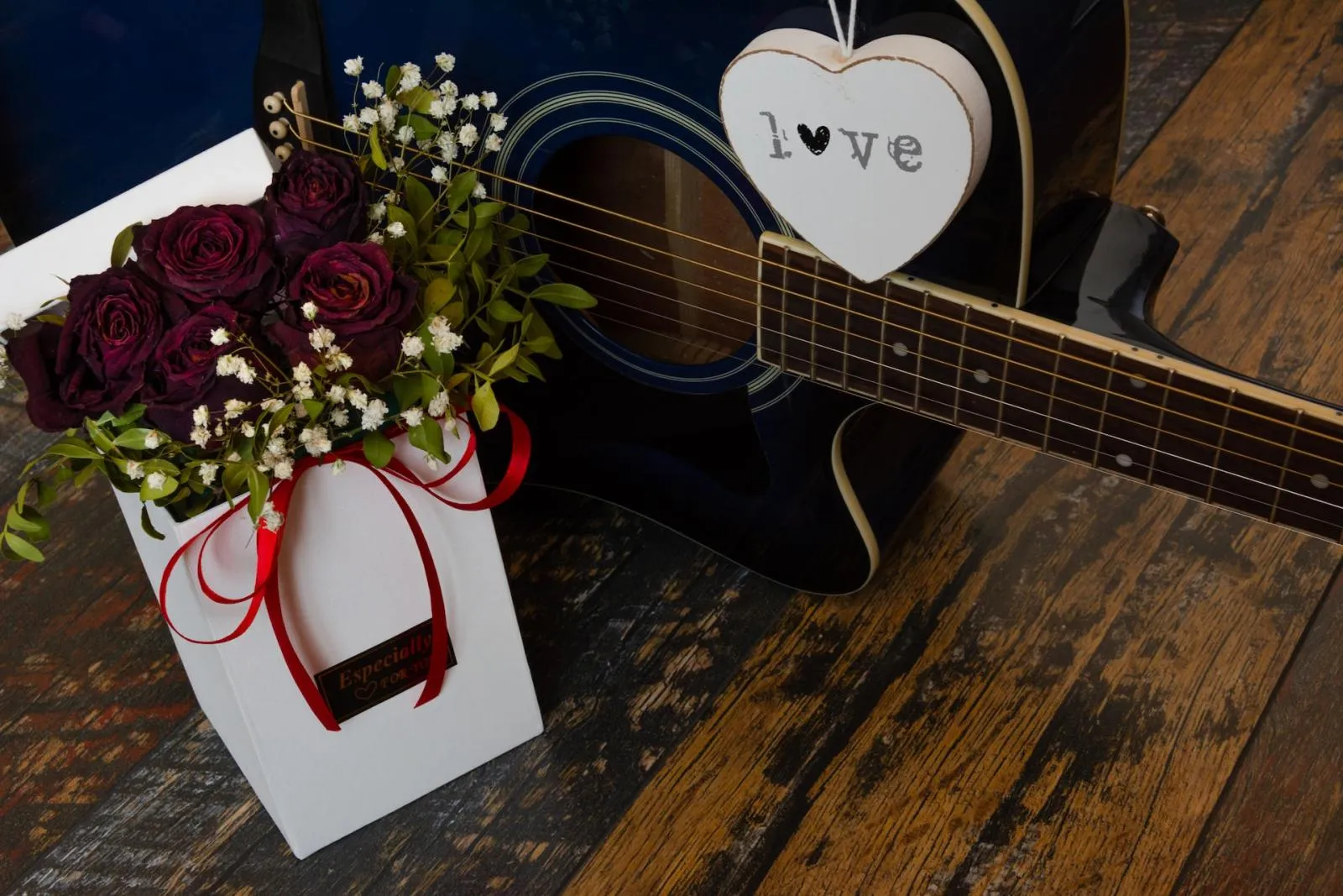 róże w pudełku z wstążką i gitara