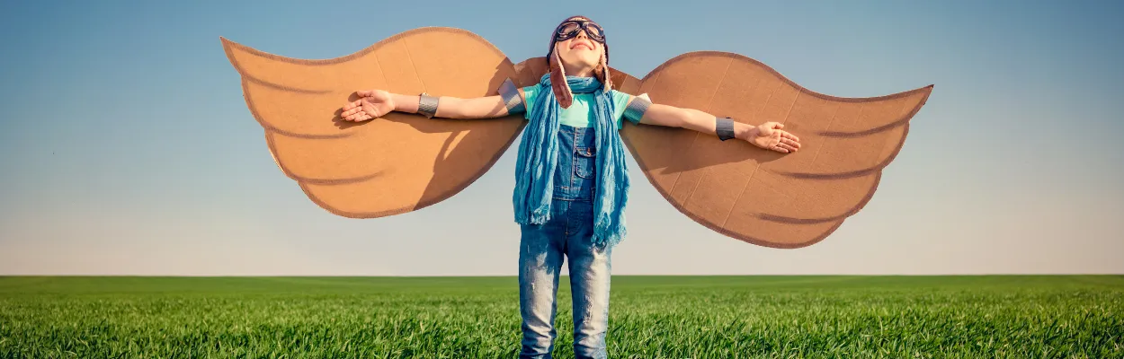 Dziewczynka stojąca na polu ze skrzydłami wykonanymi z kartonu